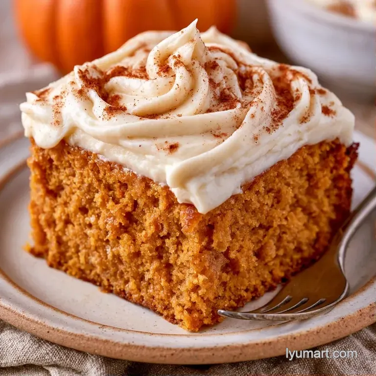 A slice of deep orange sponge cake with a smooth swirl of white frosting served on a minimalist white ceramic plate.